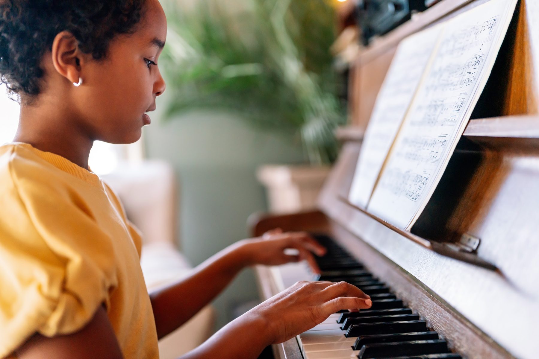 A young student playing an upright piano from sheet music