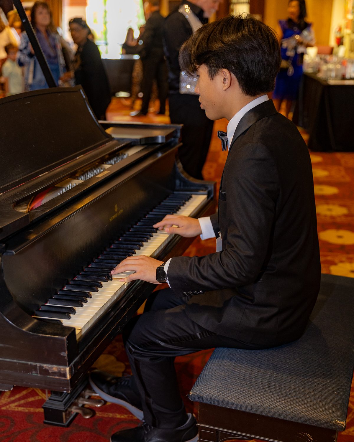 A young pianist in a tuxedo playing a grand piano at Dancing Stars 2025